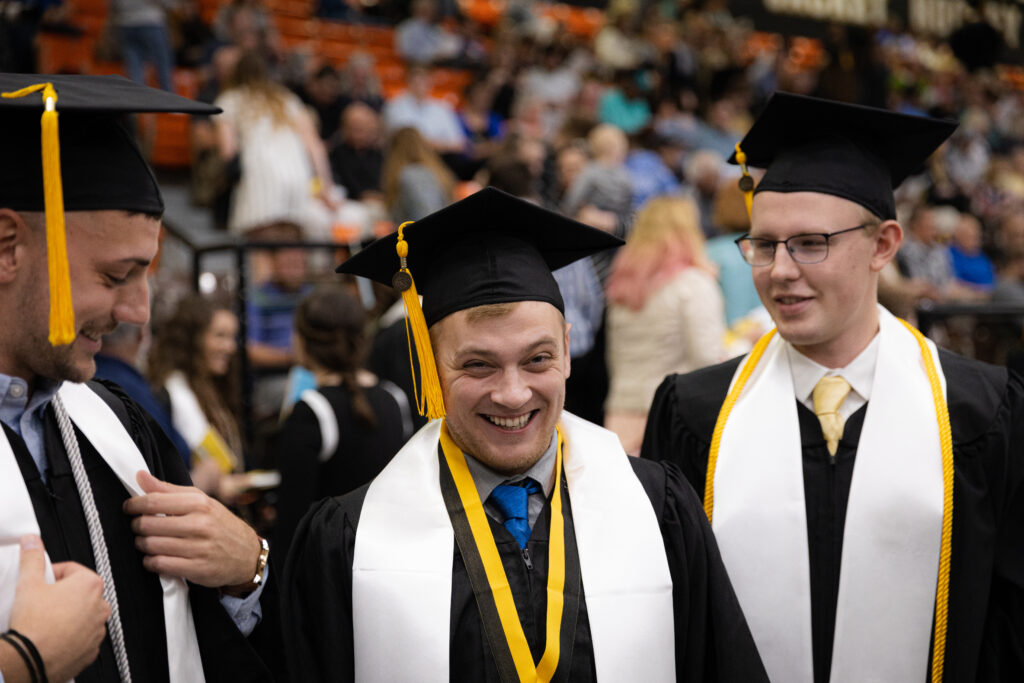 Three students in graduation caps and gowns smiling