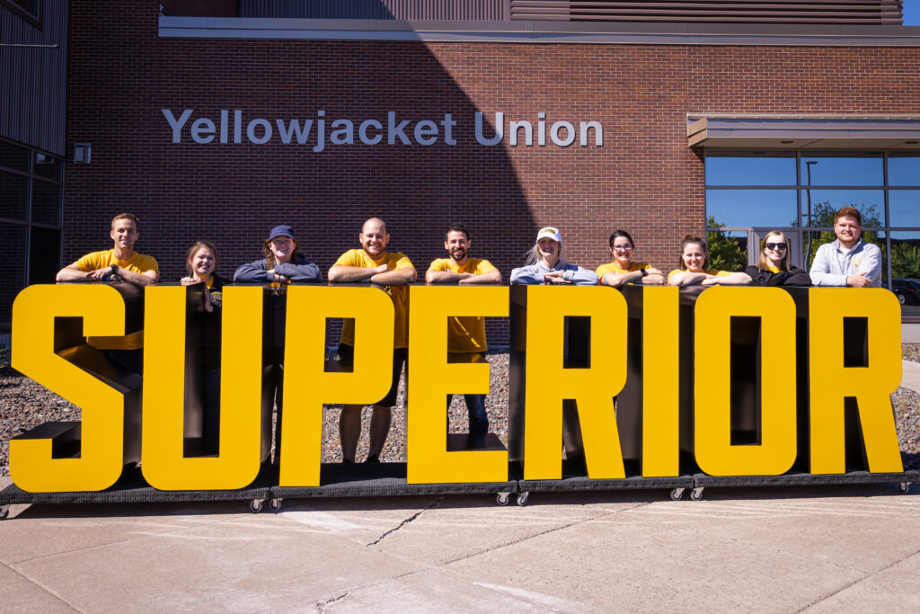 Move-in crew posing with large yellow 'SUPERIOR' letters