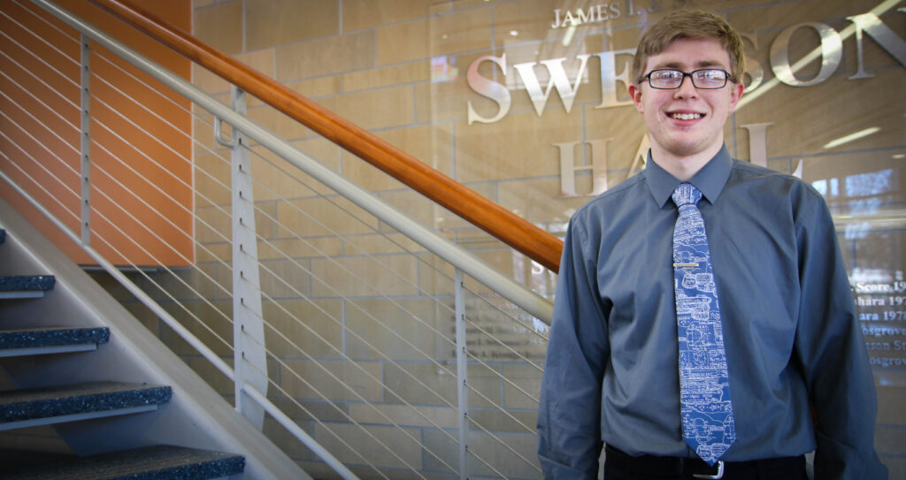 Student in front of Swenson Hall donor wall