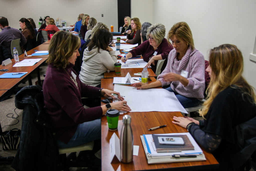 Many students discussing and drawing in a classroom