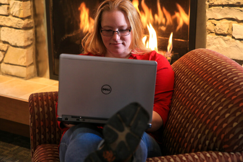 Student using laptop by fireplace