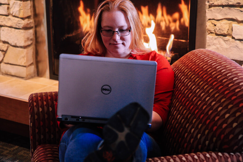 Student using laptop by fireplace