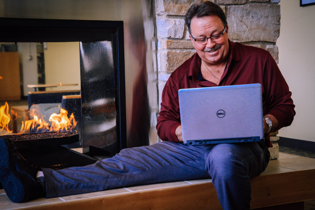 Man using laptop by fireplace