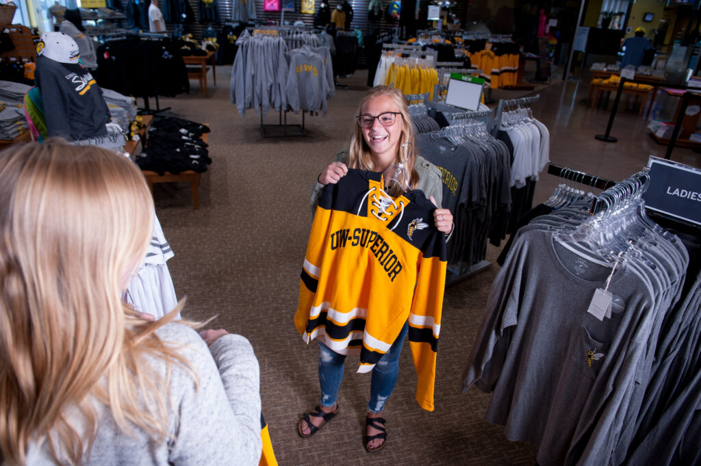 Student smiling holding UW-Superior sweatshirt in University bookstore