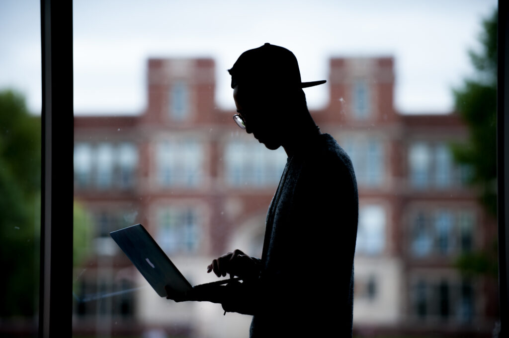 Silhouette of student using laptop