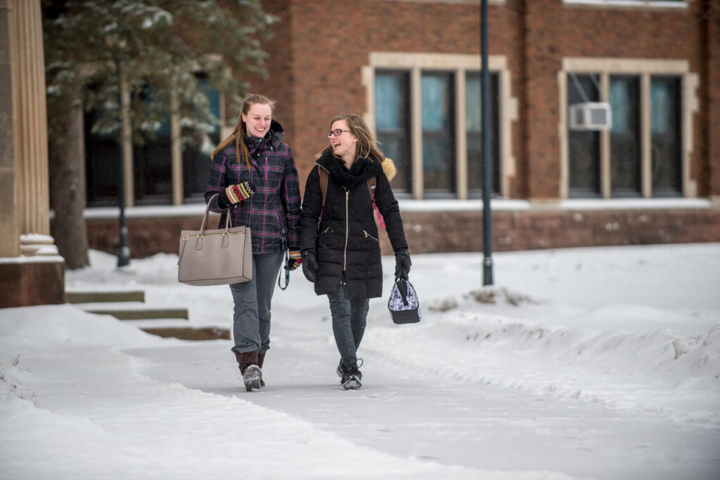 Two students walking together in snow