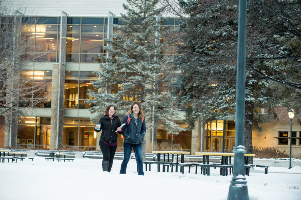 Two students walking together in the snow