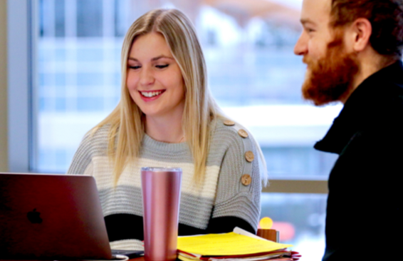 Two people sitting at a table with a computer